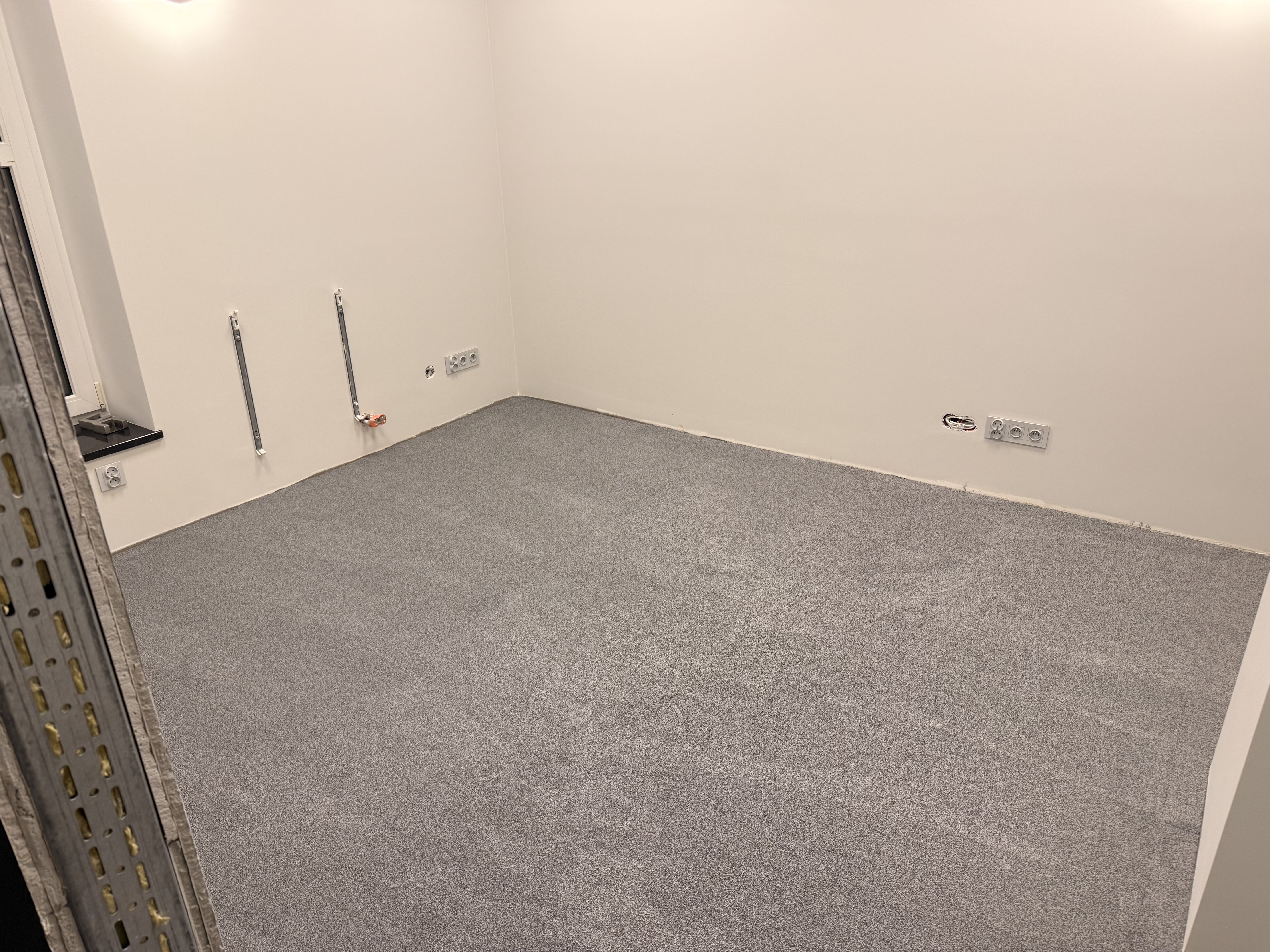 Szara wykładzina dywanowa w pomieszczeniu w trakcie wykończenia